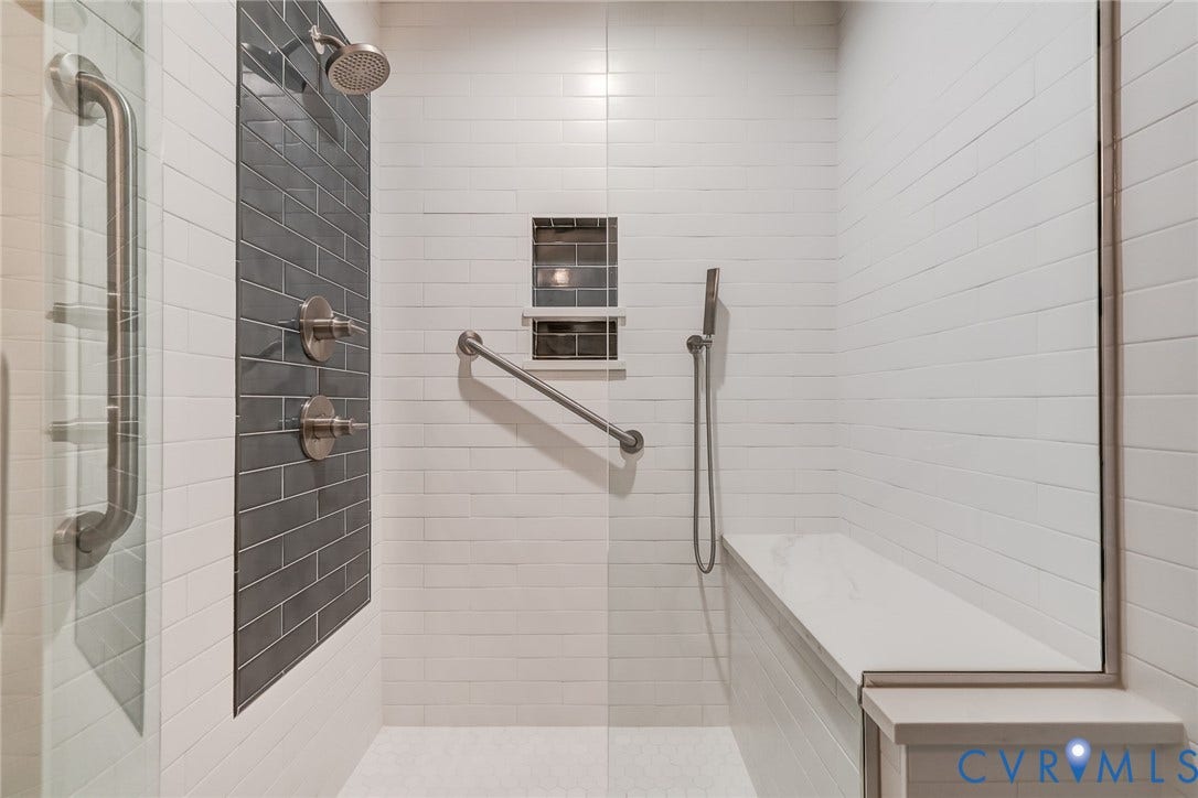 1109 Lakeland Circle, Henrico, VA 23229 Walk-in shower featuring white subway wall tile, a dark-toned tiled accent panel, a built-in bench, a wall-mounted hand shower, and brushed-finish fixtures