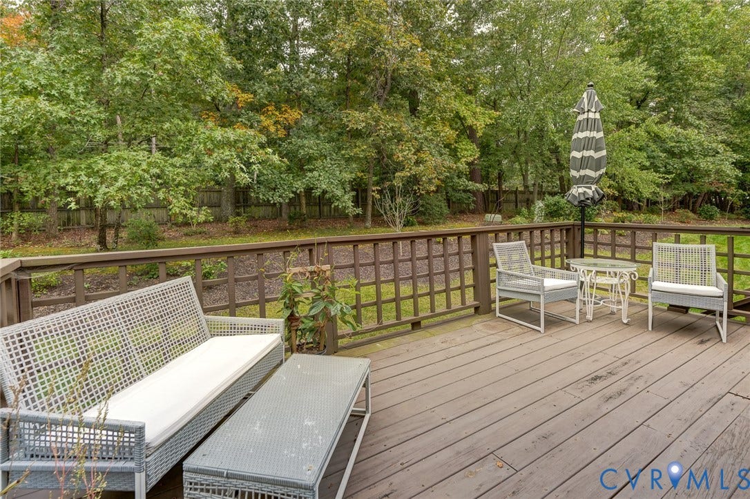 1109 Lakeland Circle, Henrico, VA 23229 Elevated wood-plank deck featuring a lattice-style perimeter railing and a backdrop of mature, dense trees