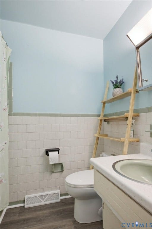 2609 Maury Road, Prince George, VA 23805 Bathroom featuring white rectangular wall tile with green bullnose trim, wood-finish flooring, a vanity with a solid-surface countertop and integrated sink, and an attached medicine cabinet