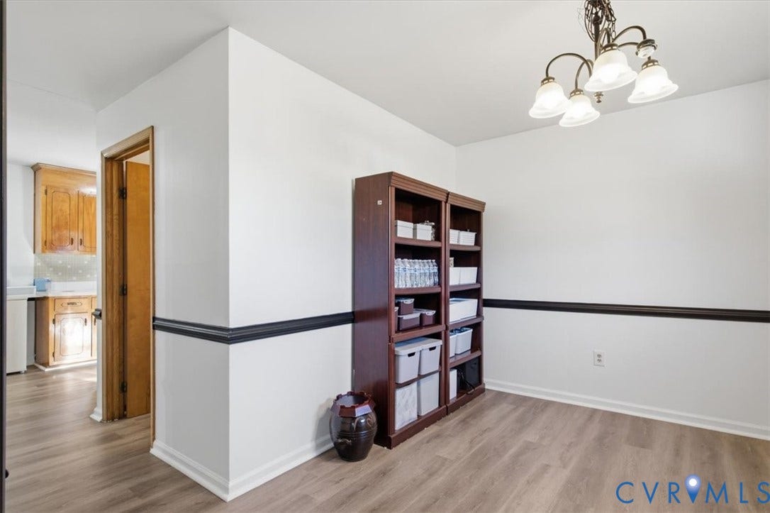 2609 Maury Road, Prince George, VA 23805 Interior space featuring wood-finish flooring, dark-toned chair rail molding, and a multi-arm chandelier with frosted glass shades