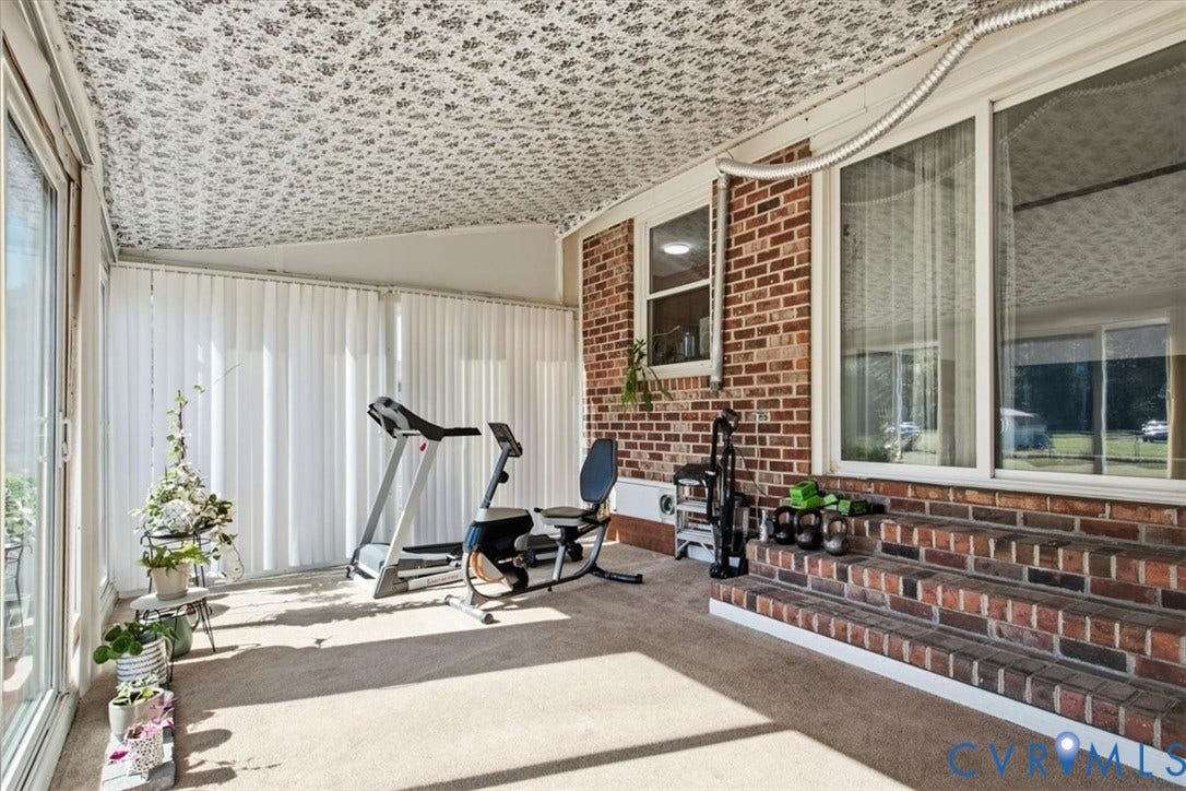 2609 Maury Road, Prince George, VA 23805 Enclosed patio featuring patterned ceiling, exposed brick wall, carpeted flooring, and multi-paneled sliding glass doors