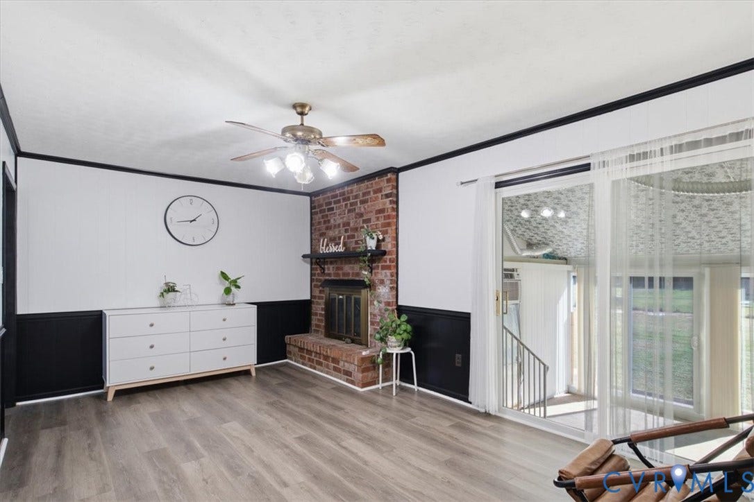 2609 Maury Road, Prince George, VA 23805 Living area featuring wood-finish flooring, a floor-to-ceiling brick fireplace with a built-in mantel, and sliding glass doors