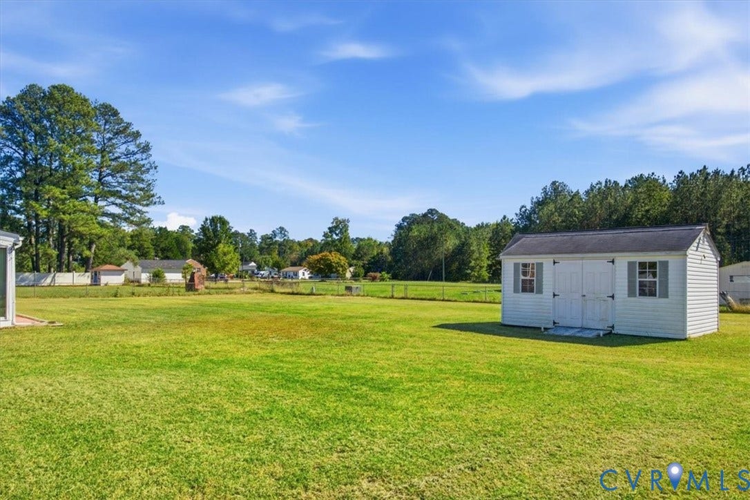 2609 Maury Road, Prince George, VA 23805 Expansive level lot featuring a grass lawn, white vinyl storage shed, perimeter fencing, and mature trees