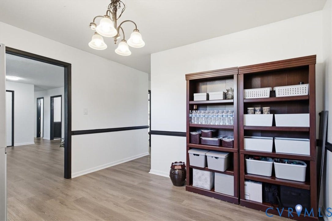 2609 Maury Road, Prince George, VA 23805 Wood-finish flooring, dark-toned crown molding and door casings, and a multi-arm chandelier with glass shades