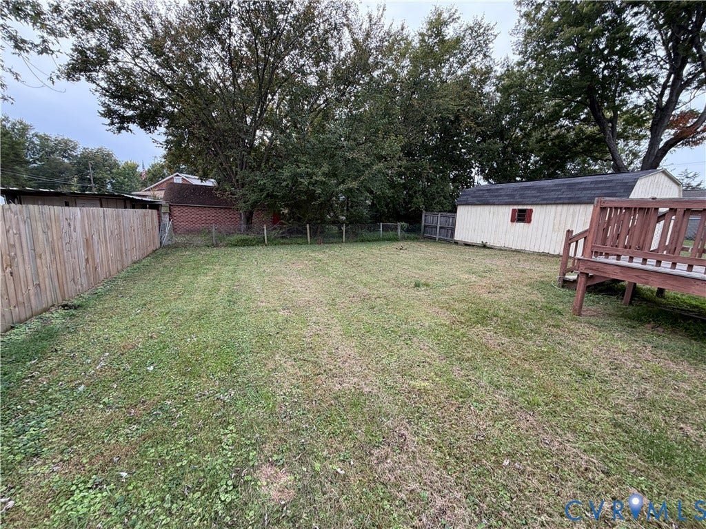 334 S 17th Avenue, Hopewell, VA 23860 Backyard featuring a grass lawn, perimeter wood fencing, detached storage structure, and raised wooden deck