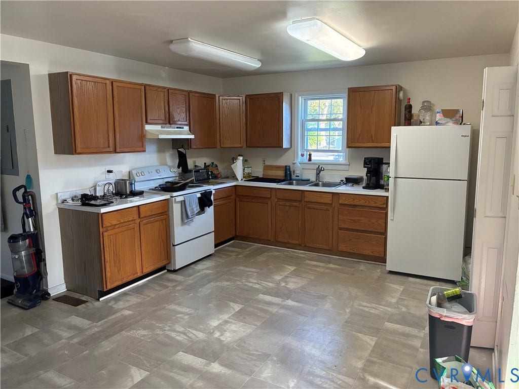 Kitchen featuring wood cabinetry, laminate countertops, a dual-basin sink, and tile-finish flooring