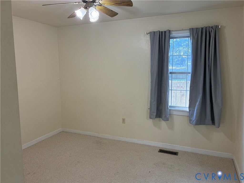 Room featuring neutral-toned carpeting, a multi-light ceiling fan, and a grid-pane window