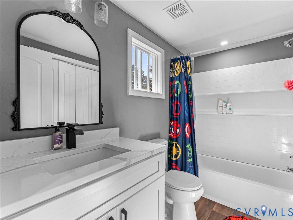 Bathroom featuring a white vanity with a stone countertop, integrated rectangular sink, and matte black faucet
