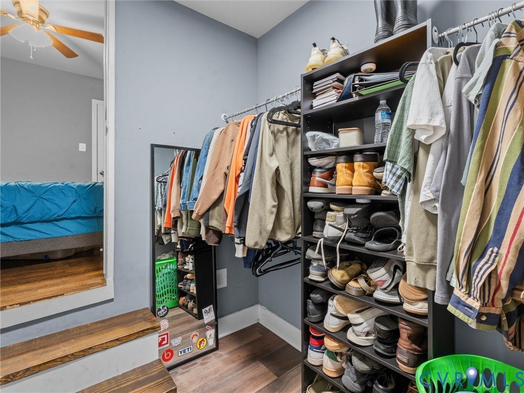 Walk-in closet featuring wood-finish flooring and metal hanging rods