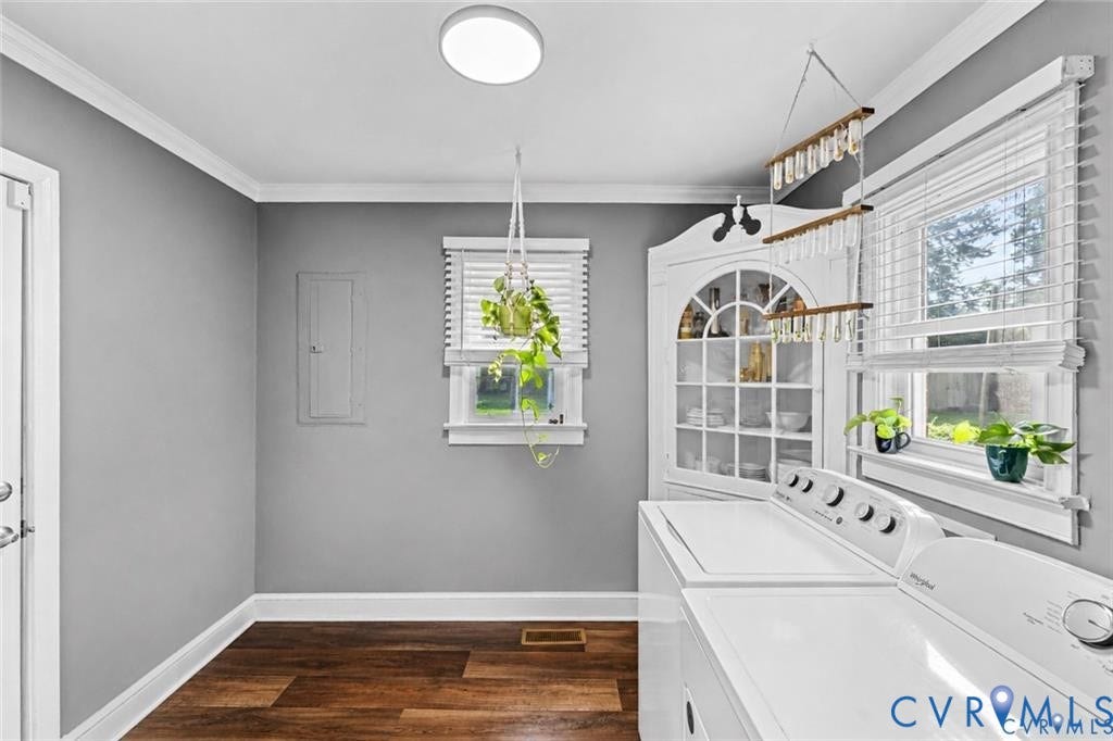 Laundry room featuring wood-finish flooring, white built-in corner cabinetry with glass-front shelving, crown molding, and dual windows with horizontal blinds