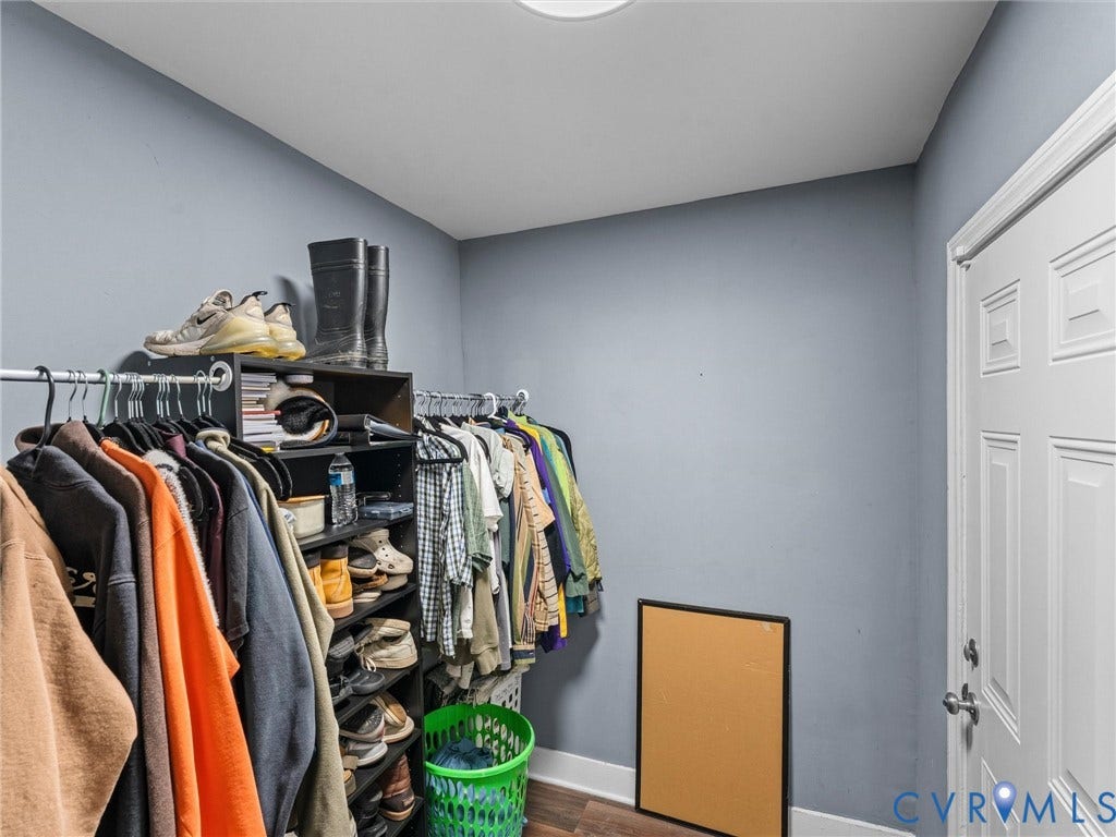 Storage space featuring metal hanging rods and wood-finish flooring
