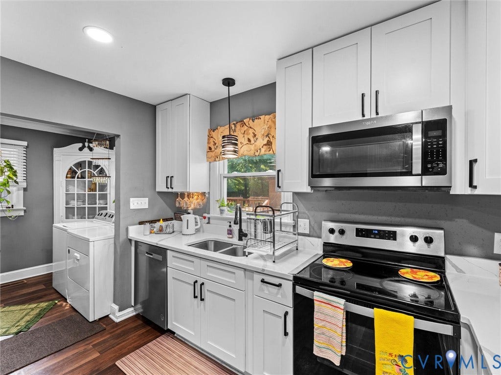 Kitchen featuring white shaker-style cabinetry, solid-surface countertops, a stainless steel over-the-range microwave, a stainless steel dishwasher, and a dark-finish faucet