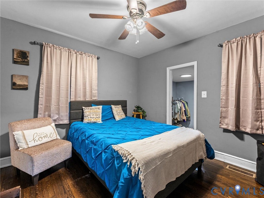 Bedroom featuring dark wood-finish flooring, neutral gray wall paint, and a ceiling-mounted light fixture with a central fan