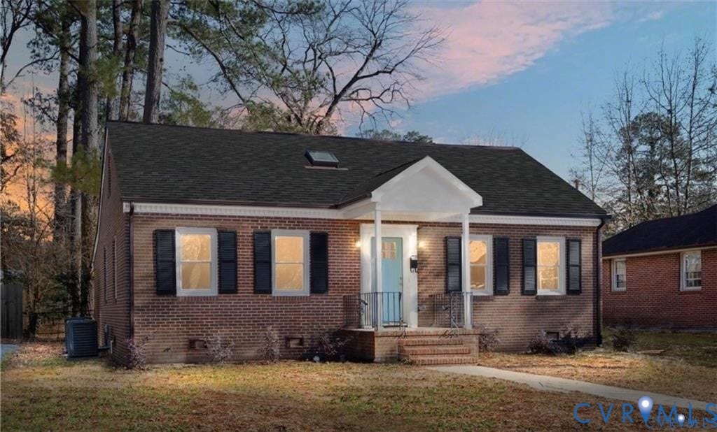 Red brick exterior featuring a covered front porch with gable roof, roof-mounted skylight, and decorative window shutters