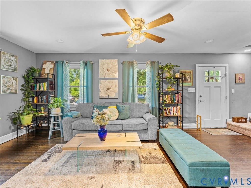 Living area featuring wood-finish flooring, recessed lighting, ceiling fan with integrated lighting, and a white six-panel door with a glass insert