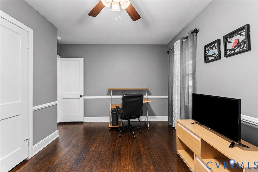 Room featuring dark-stained wood-finish flooring, chair rail molding, and a central ceiling fan with integrated lighting