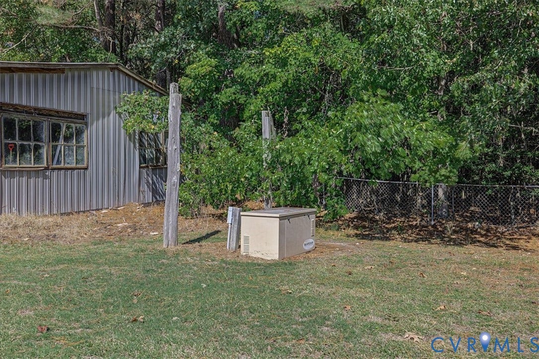 14421 Alden Road, Disputanta, VA 23842 Metal-sided exterior building featuring multi-pane windows, outdoor hardwired generator, and chain-link perimeter fencing