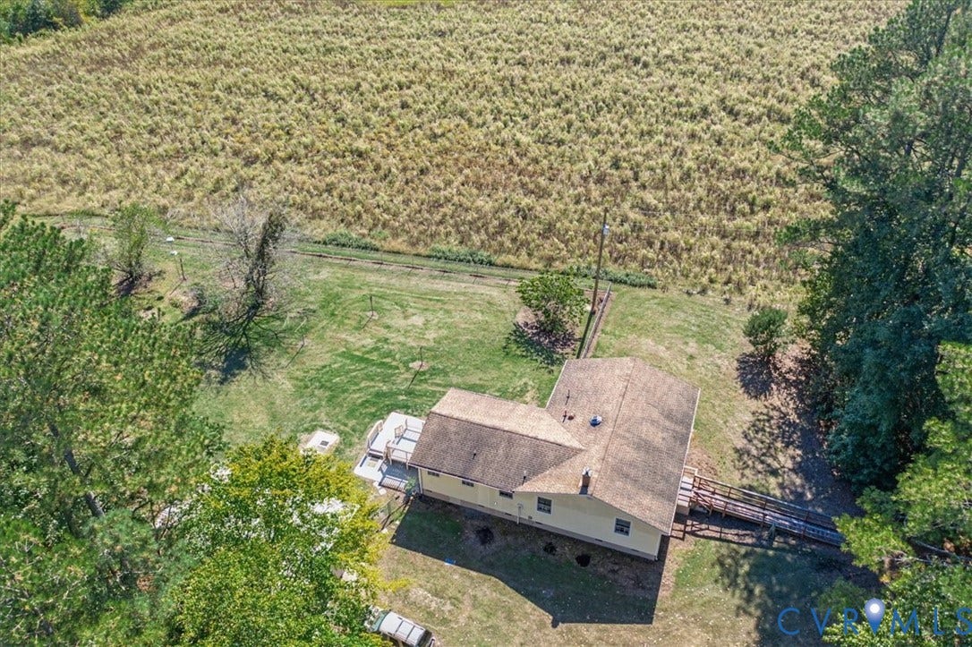 14421 Alden Road, Disputanta, VA 23842 Aerial perspective of a detached residence featuring a shingled roof, exterior deck, attached ramp, and open acreage with mature perimeter trees