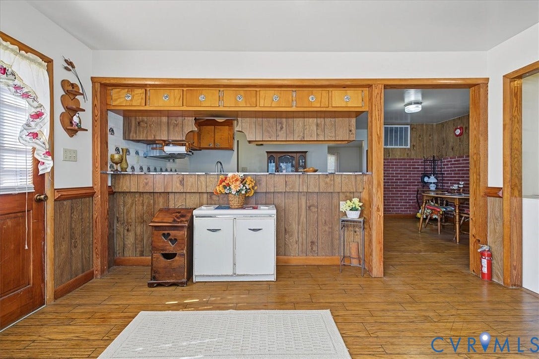14421 Alden Road, Disputanta, VA 23842 Interior space featuring wood-finish flooring, wood paneling, and an open pass-through window with wooden cabinetry