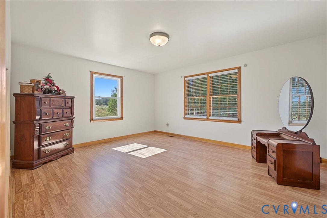 14421 Alden Road, Disputanta, VA 23842 Interior space featuring wood-finish flooring, neutral wall tones, multiple windows with natural wood trim, and a centered flush-mount light fixture