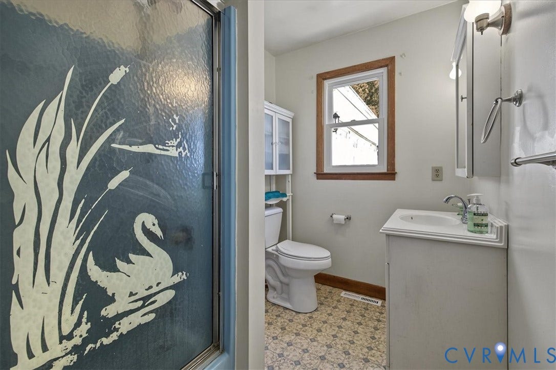 14421 Alden Road, Disputanta, VA 23842 Bathroom featuring a patterned tile floor, white vanity with integrated sink, glass shower enclosure with decorative etching, and wooden window trim
