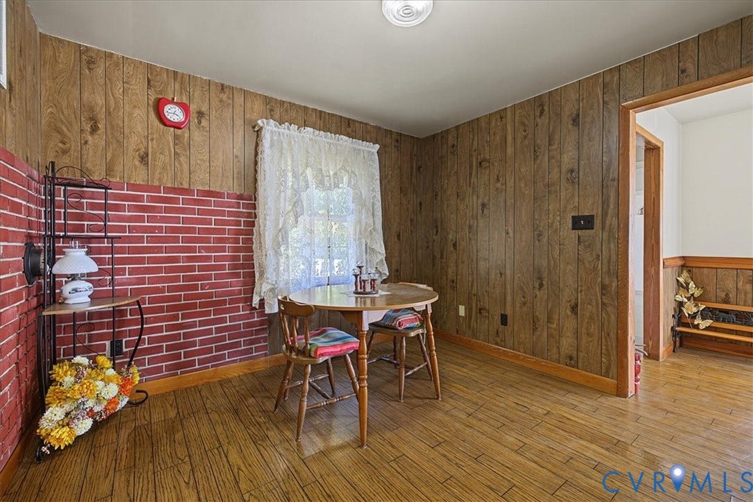 14421 Alden Road, Disputanta, VA 23842 Interior space featuring wood-finish paneling, an exposed red brick accent wall, and wood-finish flooring