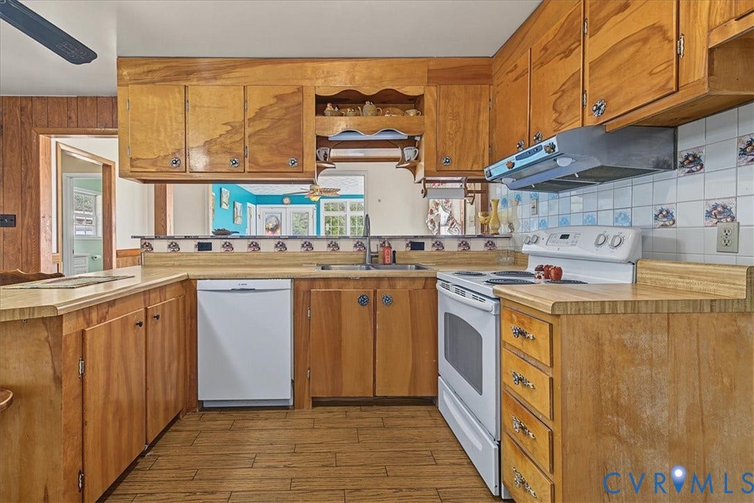 14421 Alden Road, Disputanta, VA 23842 Kitchen featuring solid wood cabinetry, wood-finish flooring, dual-basin stainless steel sink, tile backsplash, and integrated range hood