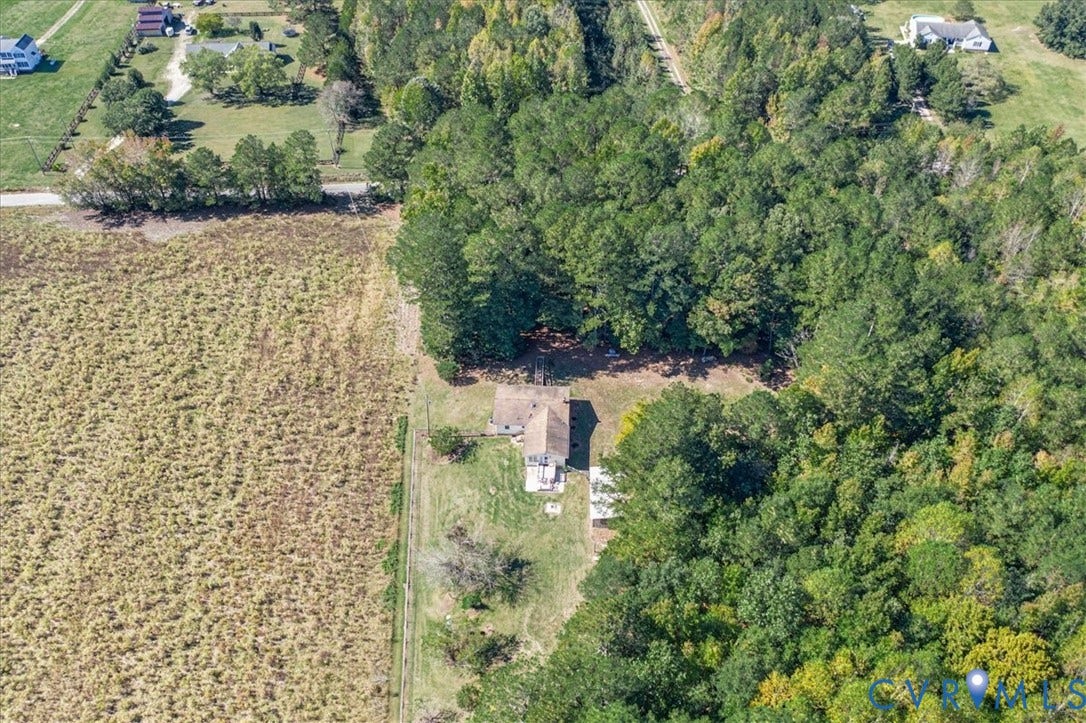 14421 Alden Road, Disputanta, VA 23842 Aerial perspective of a multi-acre property featuring expansive open field space, densely wooded areas, a detached auxiliary structure, and a fenced perimeter