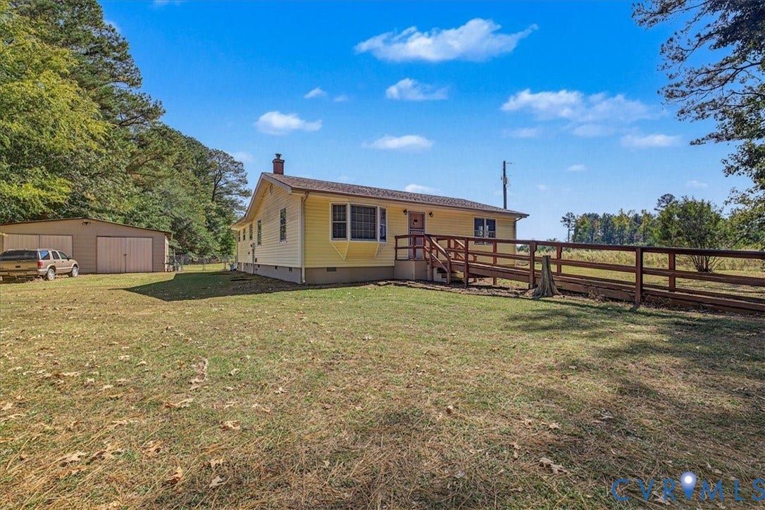 14421 Alden Road, Disputanta, VA 23842 Single-story residence featuring light yellow lap siding, a front bay window, a detached two-car garage, and a timber-framed ramp