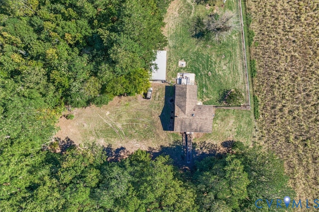 14421 Alden Road, Disputanta, VA 23842 Aerial perspective of a multi-acre property featuring a shingled roof residence, detached auxiliary structure, wooded perimeter, and open grassland