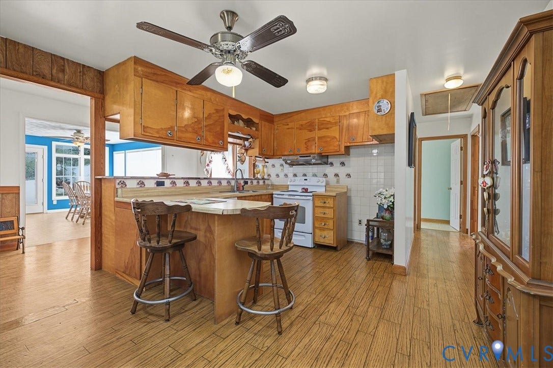 14421 Alden Road, Disputanta, VA 23842 Kitchen featuring wood-finish cabinetry, wood-finish flooring, tile backsplash, and a built-in ceiling fan with light fixture
