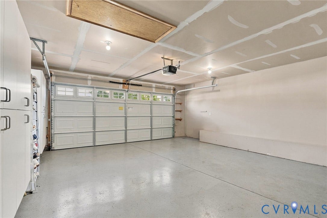 8146 Janice Avenue, Mechanicsville, VA 23111 Multi-car garage featuring a sectional door with windows, integrated ceiling lighting, epoxy-finished flooring, and built-in wall cabinetry