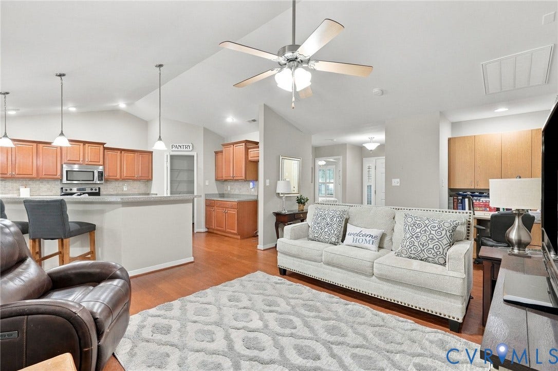 8146 Janice Avenue, Mechanicsville, VA 23111 Open-concept interior featuring vaulted ceilings, wood-finish flooring, a kitchen with wooden cabinetry, a breakfast bar, and pendant lighting