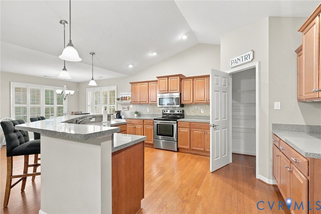 8146 Janice Avenue, Mechanicsville, VA 23111 Kitchen featuring wood cabinetry, solid-surface countertops, stainless steel appliances, wood-finish flooring, and a walk-in pantry