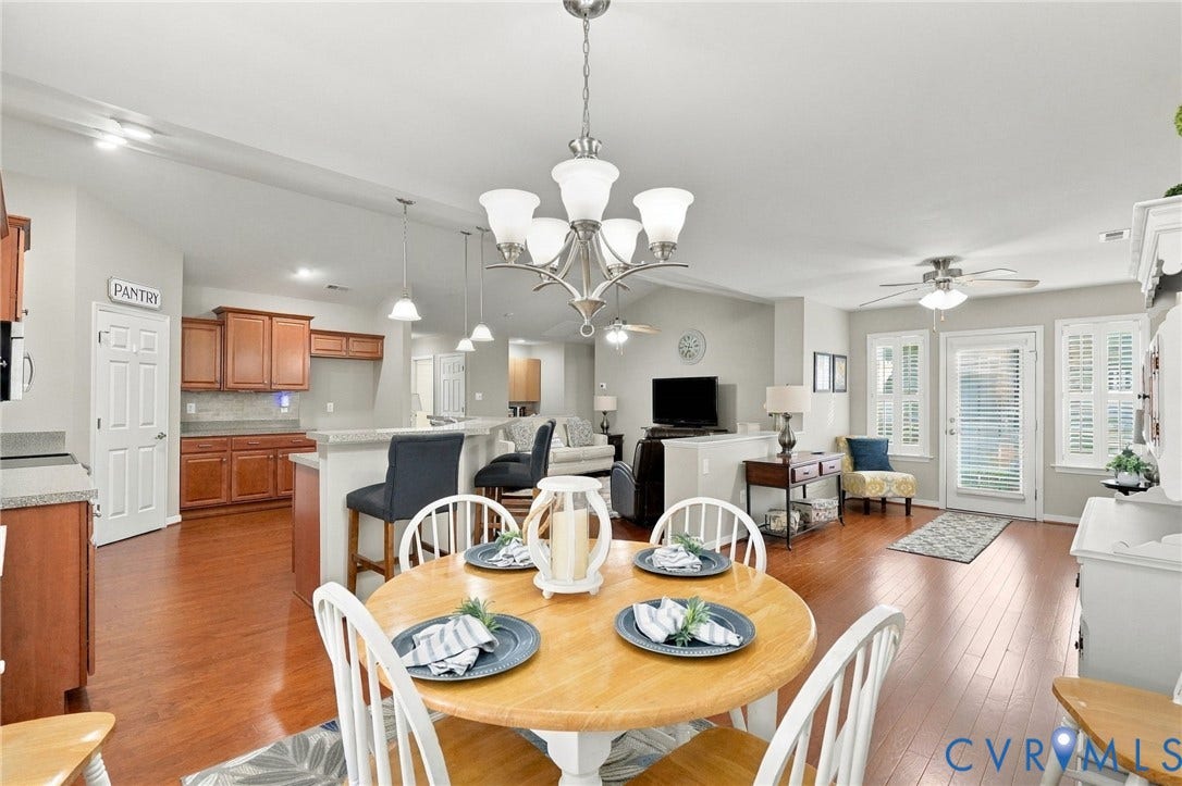 8146 Janice Avenue, Mechanicsville, VA 23111 Open-concept floor plan featuring wood-finish flooring, a tiered kitchen peninsula with stone-finish countertops, traditional wood cabinetry, and a formal chandelier fixture