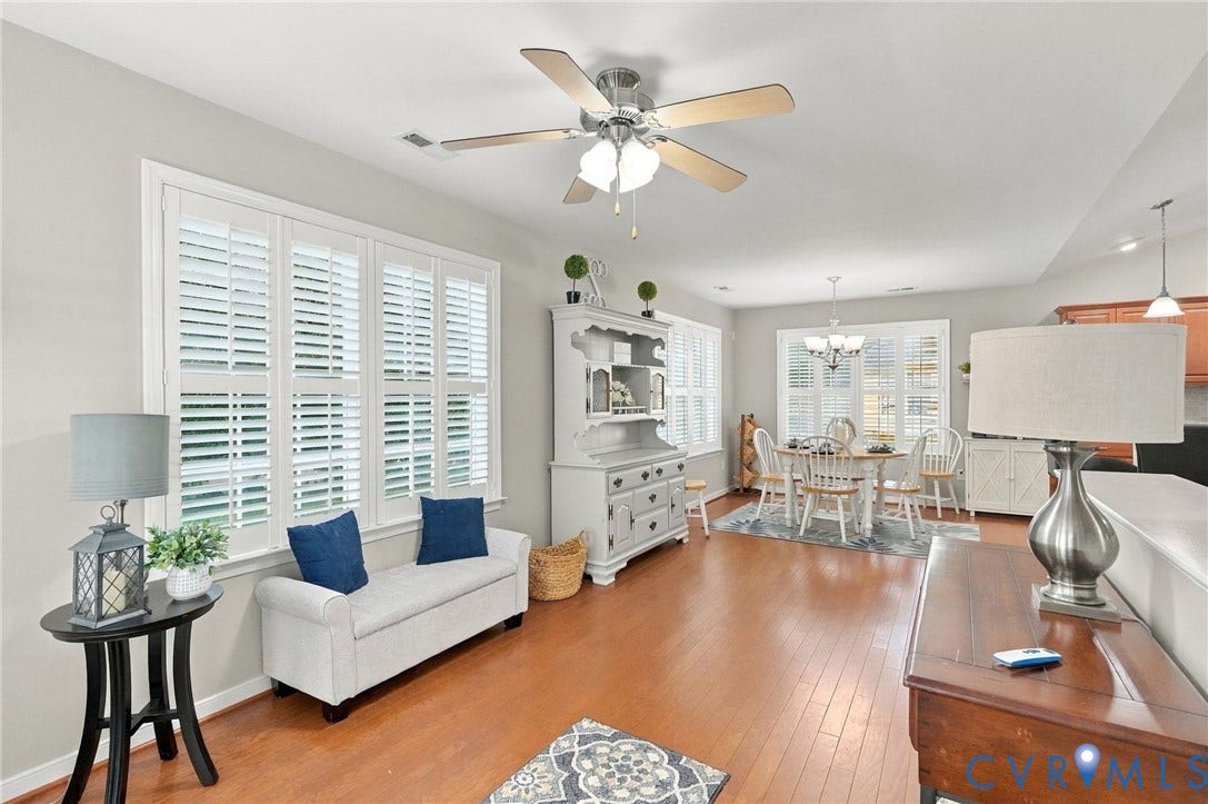 8146 Janice Avenue, Mechanicsville, VA 23111 Open-concept area featuring wood-finish flooring, plantation shutters, a ceiling fan with integrated lighting, and a multi-light chandelier