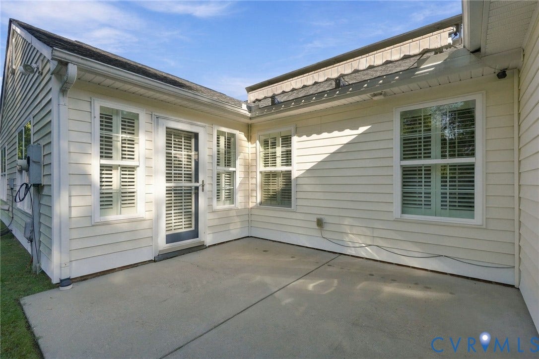 8146 Janice Avenue, Mechanicsville, VA 23111 Exterior concrete patio featuring light-toned horizontal siding, single-hung windows with exterior shutters, and a full-view glass storm door