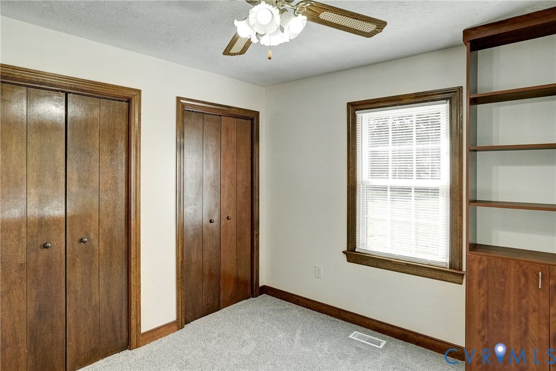 4130 Charles City Road, Charles City, VA 23231 Room featuring dual wooden closet doors, a built-in wooden shelving unit, neutral carpeting, and a ceiling-mounted light fixture