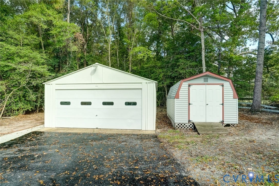 4130 Charles City Road, Charles City, VA 23231 Detached metal garage with sectional door and accompanying storage shed featuring gambrel roof and double doors