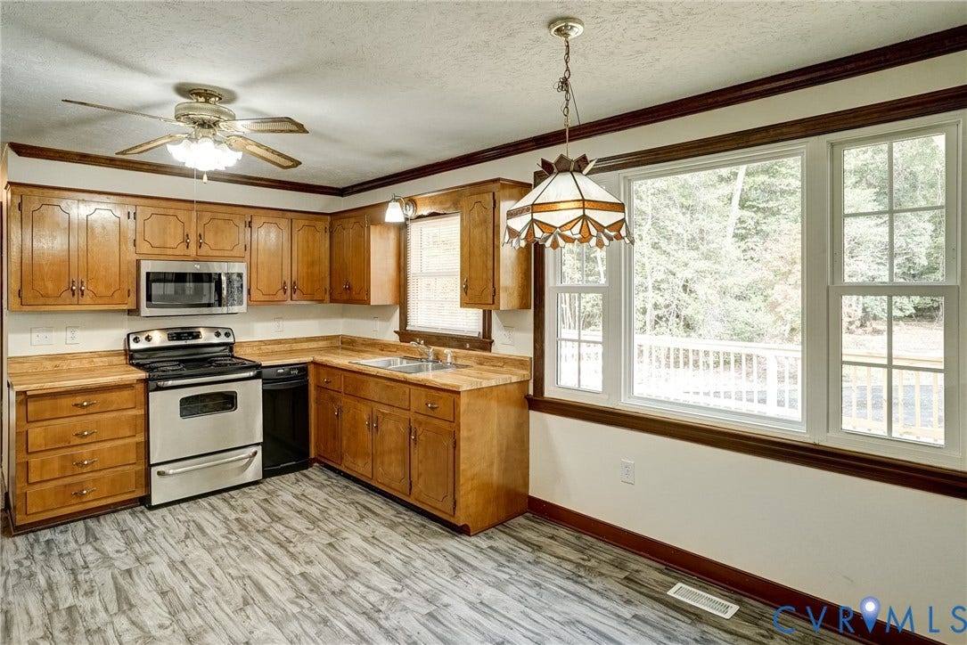 4130 Charles City Road, Charles City, VA 23231 Kitchen featuring wood cabinetry, stainless steel appliances, wood-finish flooring, crown molding, and large windows
