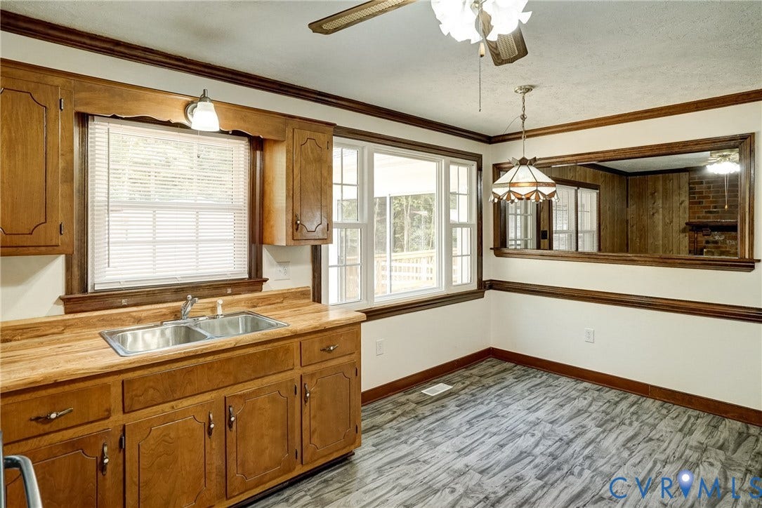 4130 Charles City Road, Charles City, VA 23231 Kitchen featuring wood cabinetry, integrated double-basin stainless steel sink, wood-finish countertop, decorative crown molding, and a wall-mounted mirror with wood frame