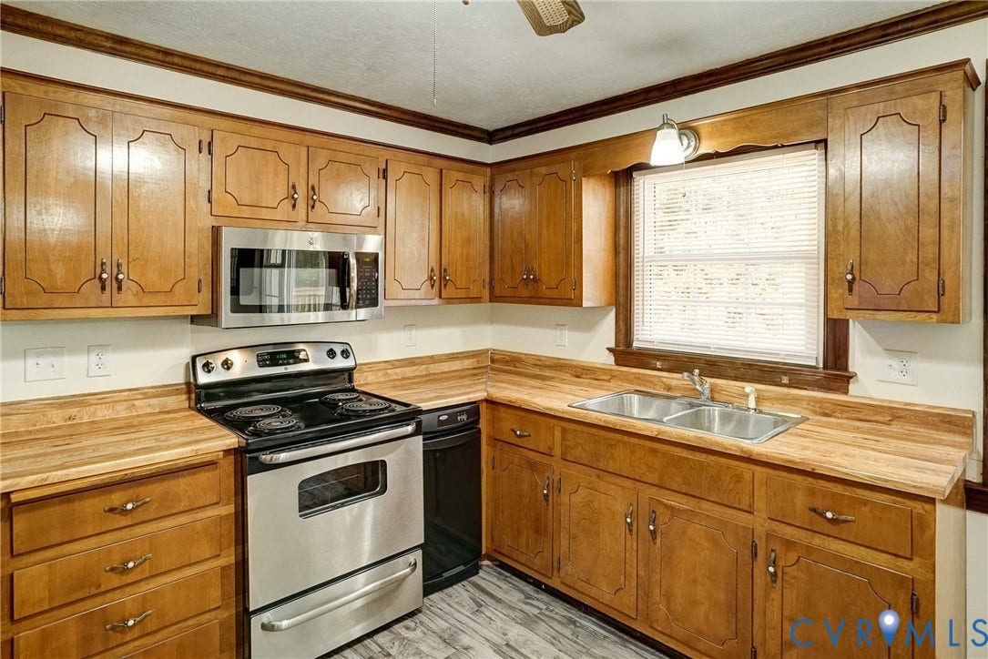4130 Charles City Road, Charles City, VA 23231 Kitchen featuring stained wood cabinetry, stainless steel oven with integrated microwave, wood-finish countertops, dual-basin stainless steel sink, and wood-finish flooring