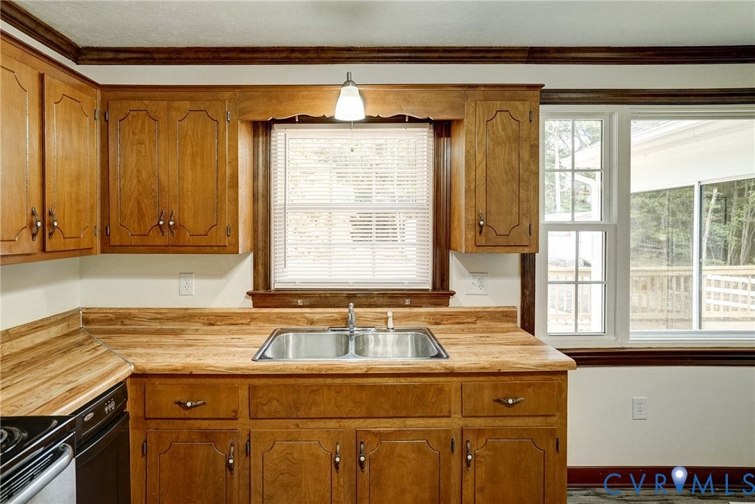 4130 Charles City Road, Charles City, VA 23231 Kitchen featuring wood cabinetry, butcher-block countertops, a stainless steel double-basin sink, crown molding, and multi-pane windows