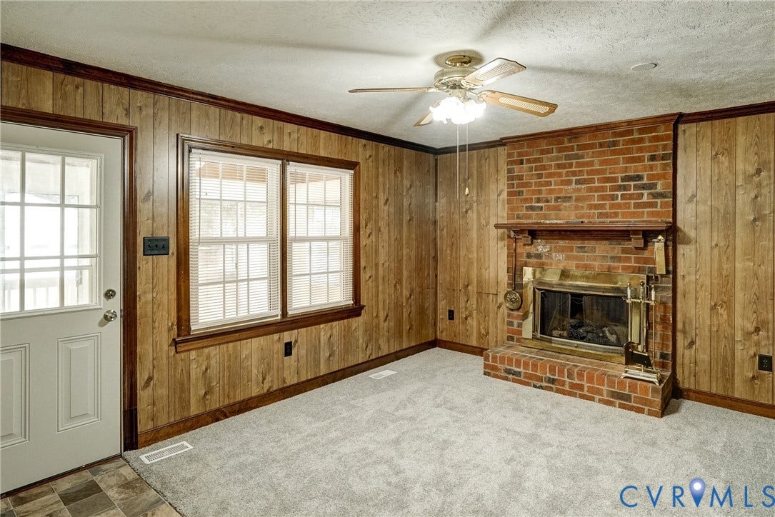 4130 Charles City Road, Charles City, VA 23231 Interior space featuring wood-panel wall finish, full-height brick fireplace with a built-in mantel, multi-pane exterior door, and a ceiling-mounted light fixture with a fan