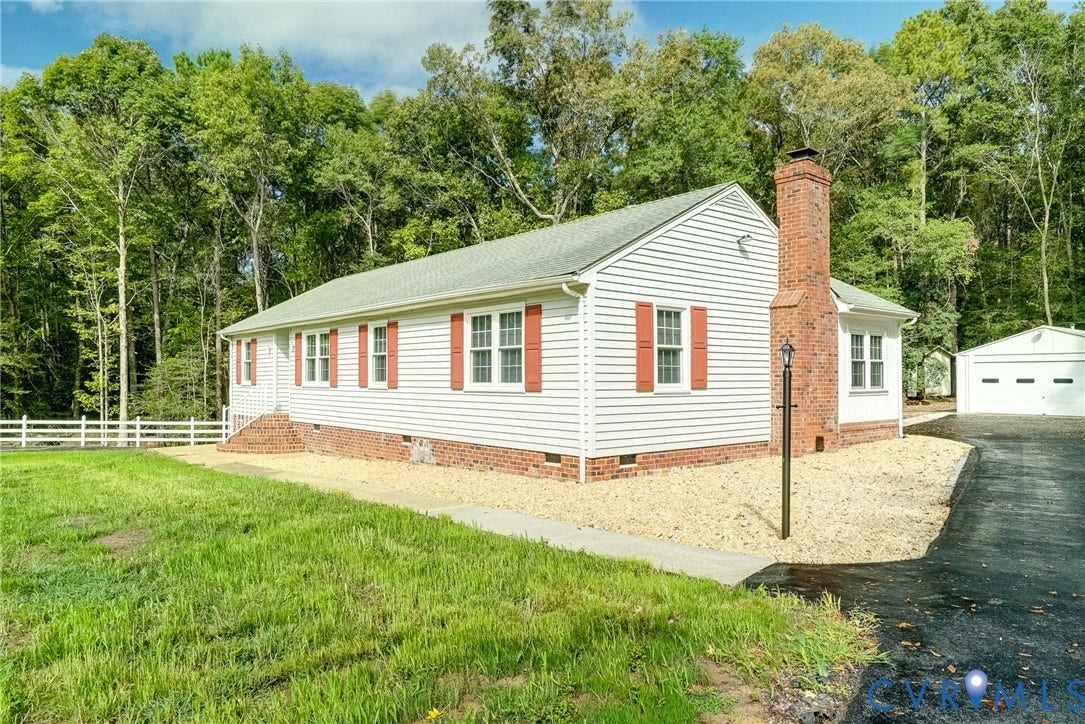 4130 Charles City Road, Charles City, VA 23231 Single-story exterior featuring white horizontal siding, red brick foundation and chimney, decorative window shutters, and a detached garage