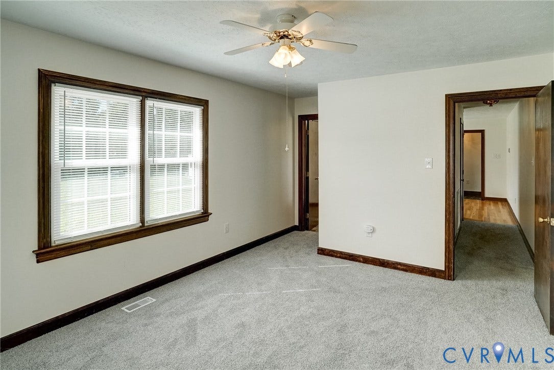 4130 Charles City Road, Charles City, VA 23231 Room featuring wall-to-wall carpeting, dual-pane windows with wood trim, and a ceiling-mounted light fixture with a fan