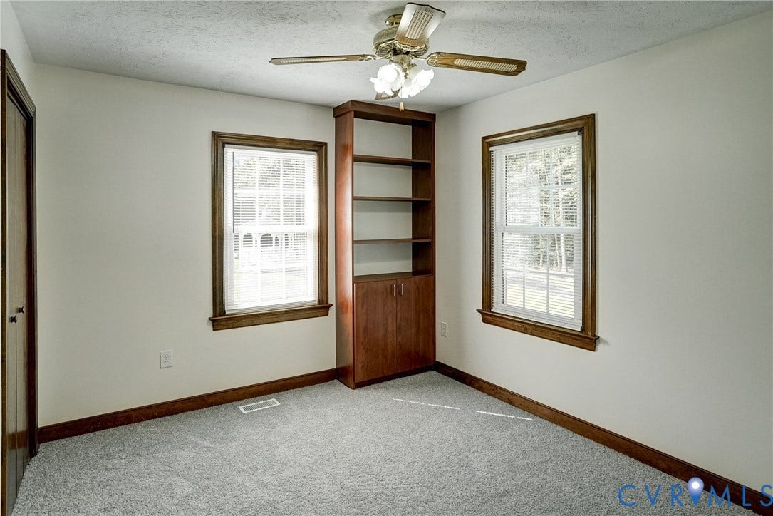 4130 Charles City Road, Charles City, VA 23231 Built-in wooden shelving unit with lower cabinetry, double-hung windows with wood trim, and a ceiling fan with integrated lighting