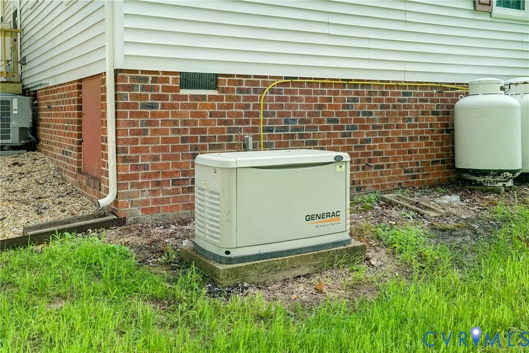 4130 Charles City Road, Charles City, VA 23231 Permanent home standby generator on a concrete pad, exterior brick foundation, and dual propane tanks