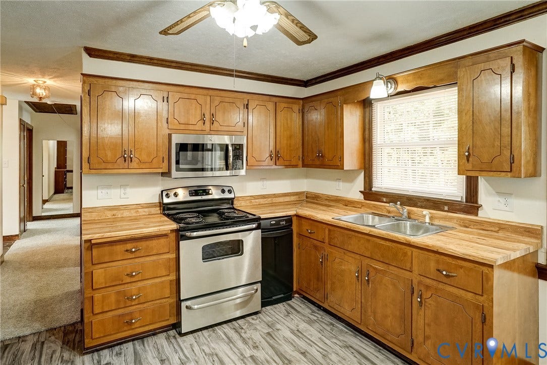 4130 Charles City Road, Charles City, VA 23231 Kitchen featuring wooden cabinetry, butcher-block countertops, stainless steel appliances, a double-basin sink, and gray wood-finish flooring