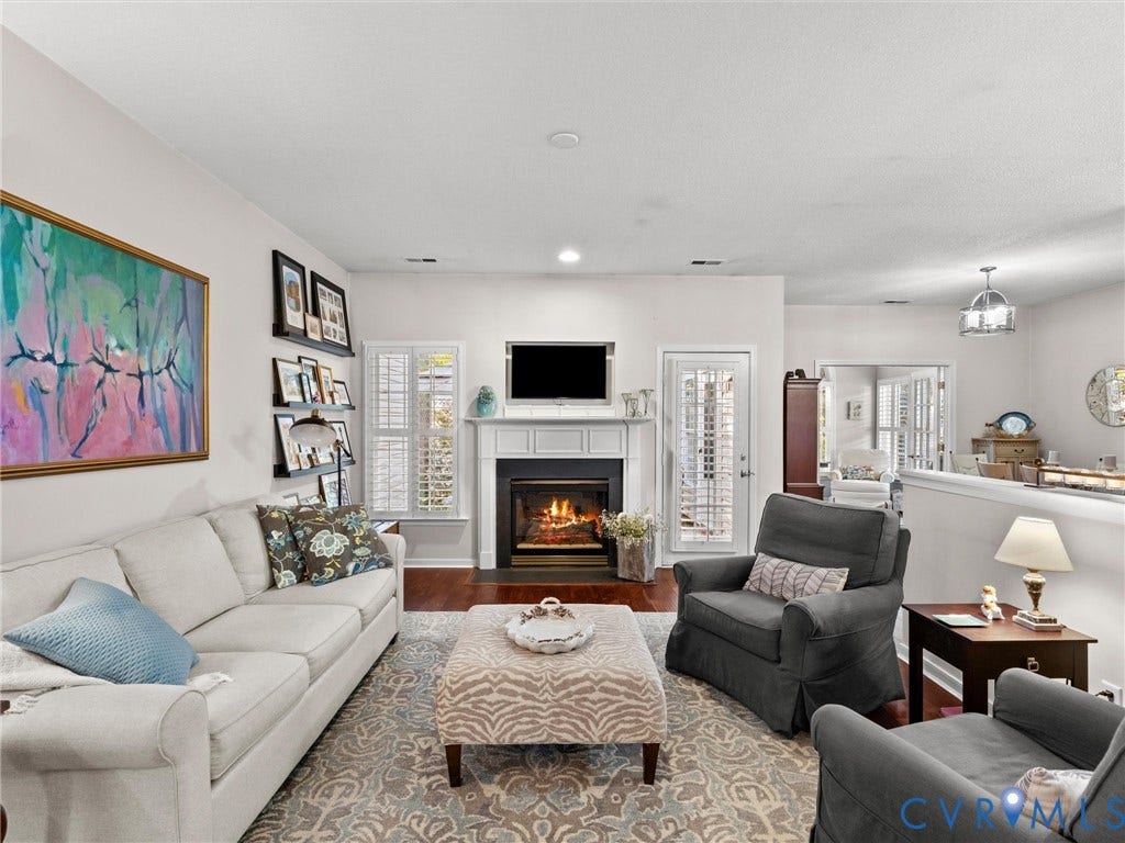 4105 English Holly Circle, Glen Allen, VA 23294 Living area featuring wood-finish flooring, a fireplace with a white mantel, and plantation shutters